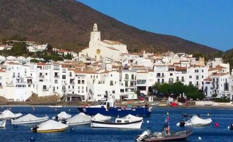 Casas blancas de Cadaqués junto al mar y barcas en primer plano