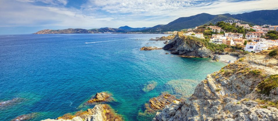 Acantilados rocosos del Cap de Creus con el mar Mediterráneo y un velero