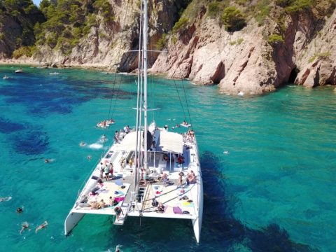 Catamarán fondeado en una cala de la Costa Brava con bañistas haciendo snorkel