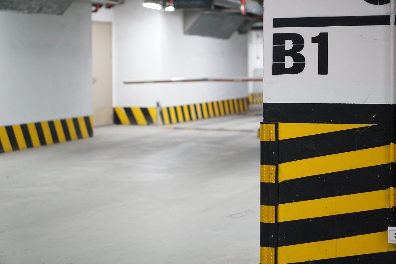 Estacionamiento subterr&aacute;neo amplio con muchos coches y plazas de garaje.