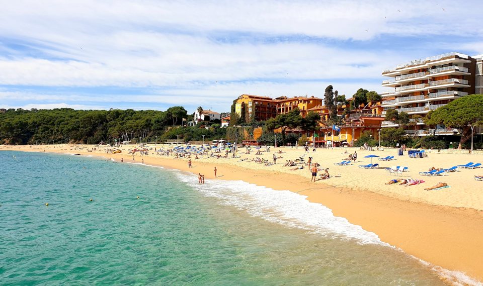 Platja de Fenals in Lloret de Mar with calm water and pine trees