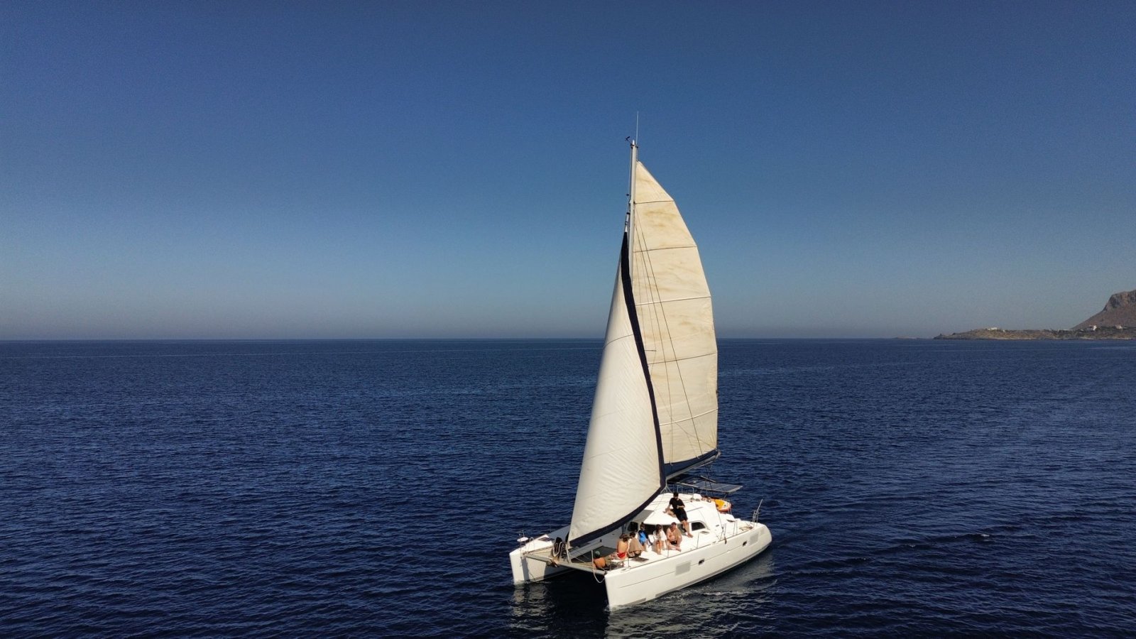 Catamarán navegando en mar abierto bajo cielo despejado, aventura náutica serena.