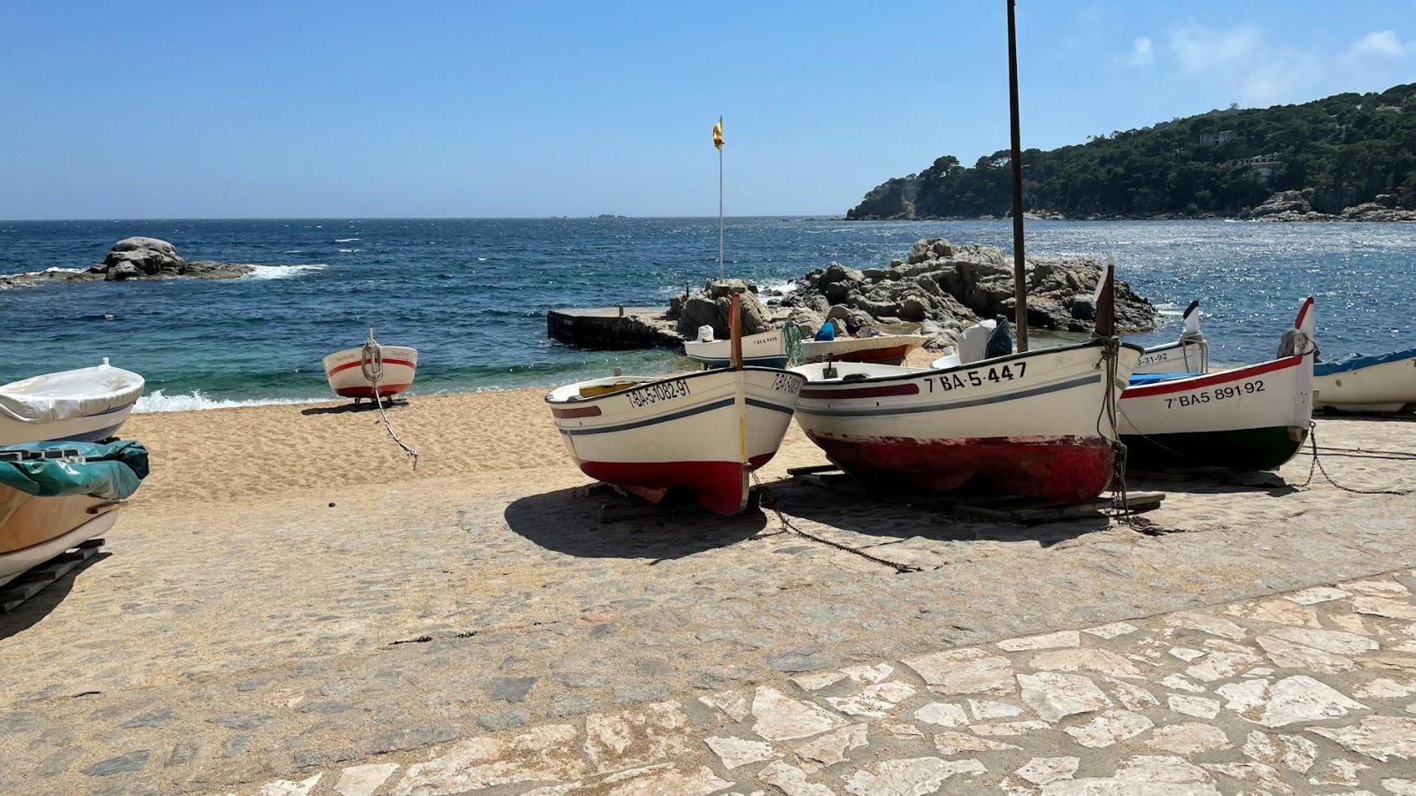 A picturesque scene of colourful fishing boats resting on a sandy beach by the ocean.
