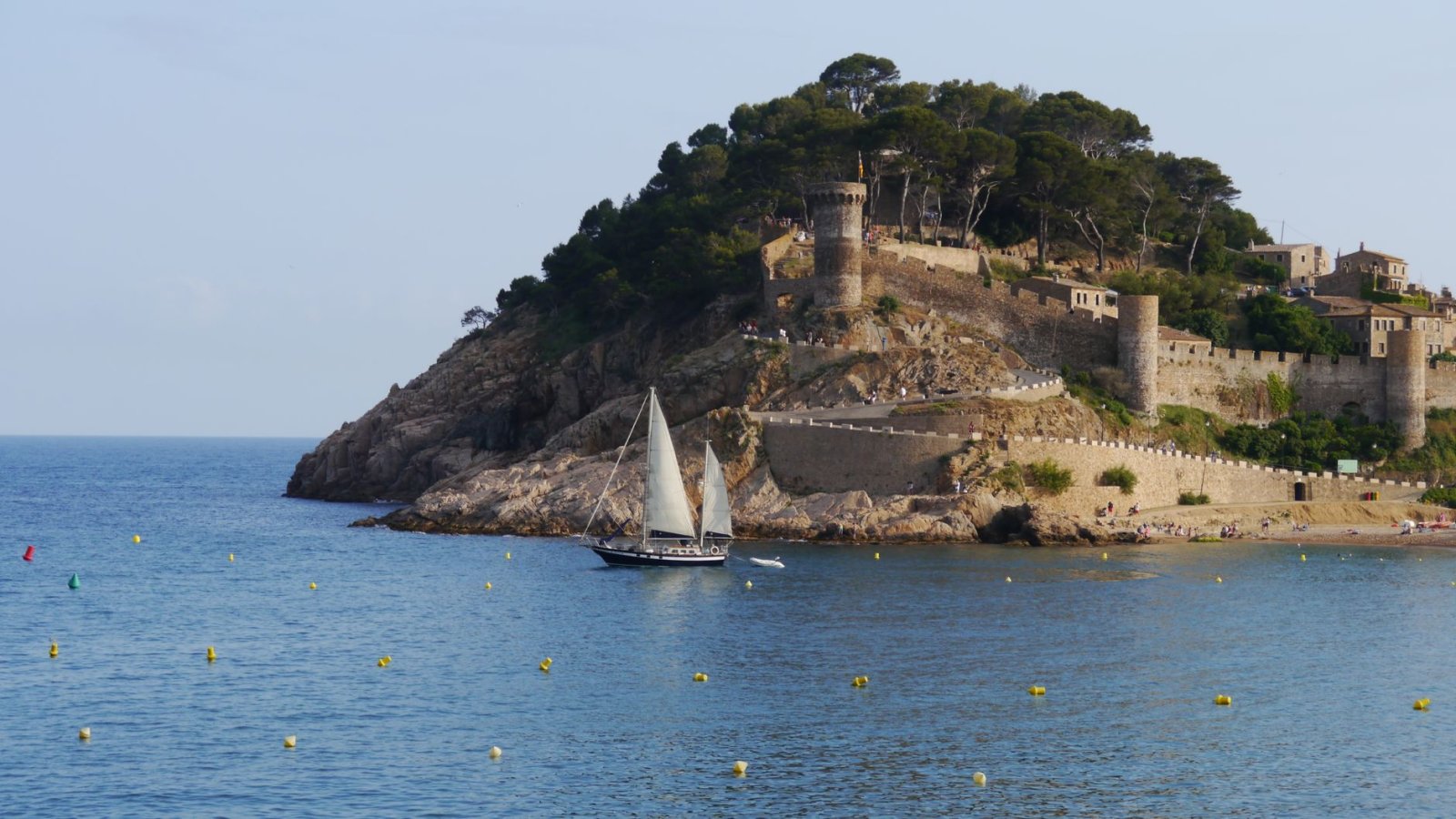 Castillo hist&oacute;rico de Tossa de Mar con velero y mar Mediterr&aacute;neo.