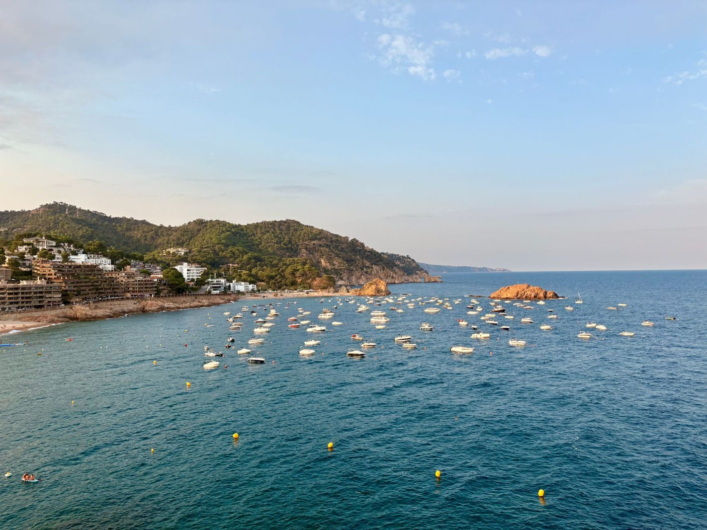 Costa de Tossa de Mar, Espa&ntilde;a, con barcos amarrados bajo cielo azul.