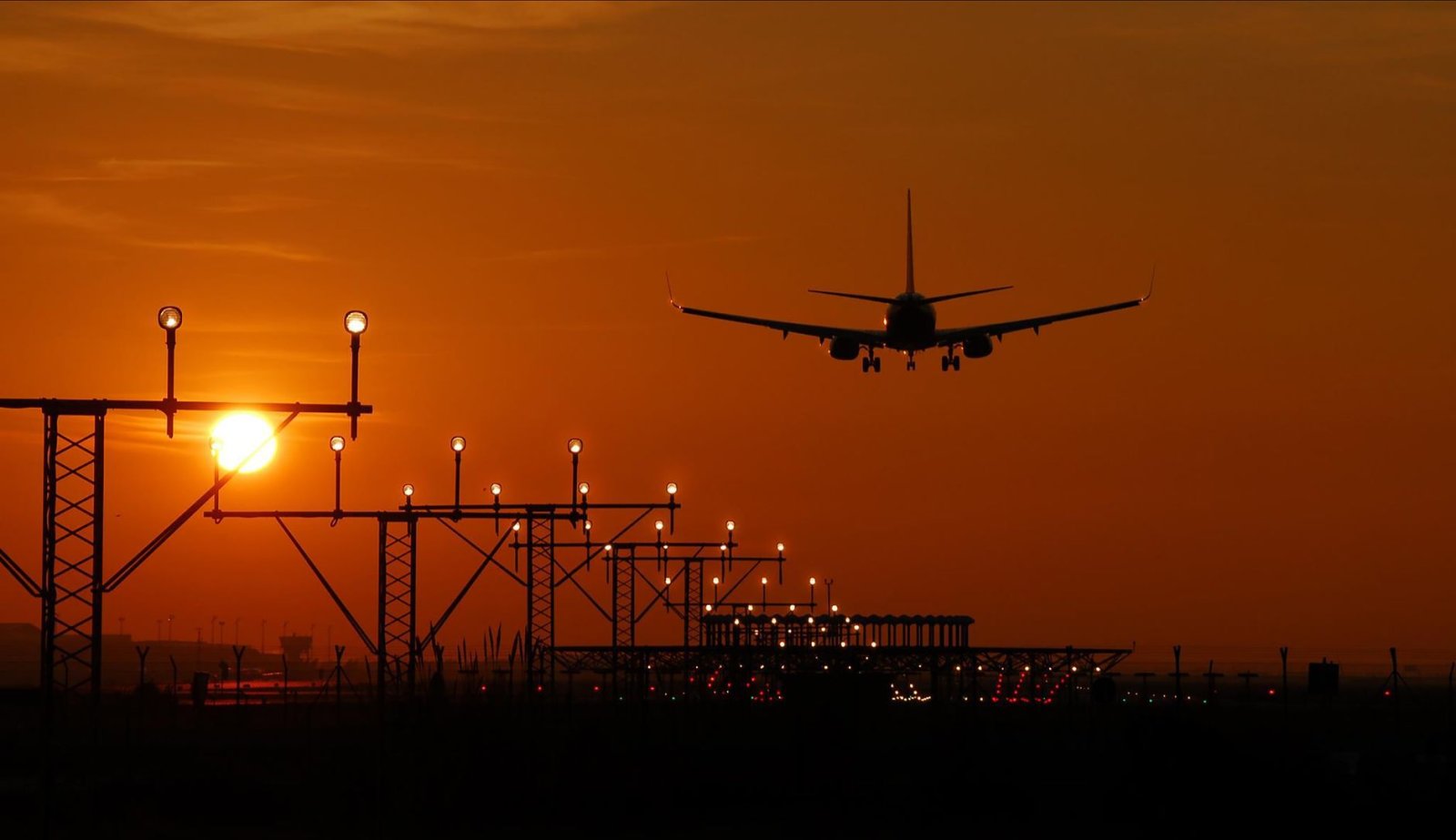 Avión aterrizando al atardecer en Barcelona, cielo naranja vibrante.