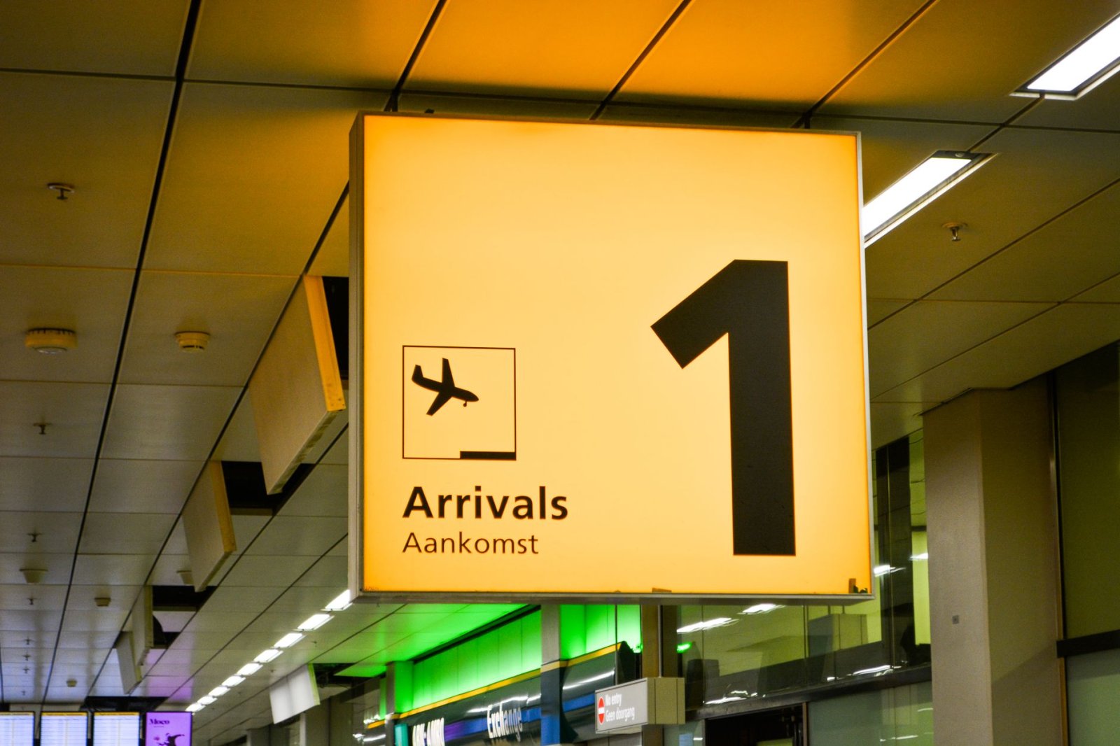 Letrero de llegadas brillante con símbolo de avión en terminal de aeropuerto.